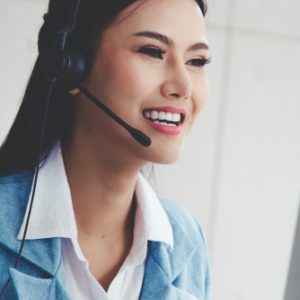 A young East Asian business woman smiling while wearing a phone headset.
